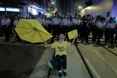 A protester raises an umbrella sitting in front of a line of police officers outside the Chinese central government&#039;s liaison office in Hong Kong, Sunday, Nov. 6, 2016. Thousands of protesters marched in Hong Kong on Sunday, demanding that China&#039;s central government stay out of a political dispute in the southern Chinese city after Beijing indicated that it would intervene to deter pro-independence advocates. (AP Photo/Vincent Yu)