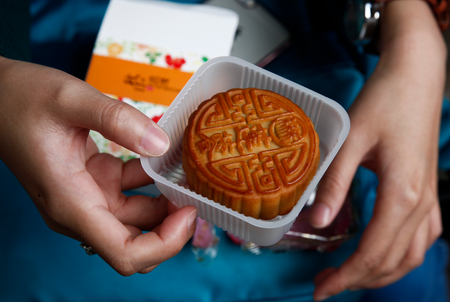 epa05540266 A college-level Indonesian student opens a box of mooncakes as part of an activity held to teach foreign students about the Mid-Autumn Festival at Jingshan Park in Beijing, China, 15 September 2016. China observes the Mid-Autumn Festival or Mooncake Festival on 15 September, which this year is the 15th day of the eighth month in the lunar calendar where traditionally family members and friends gather to admire the mid-autumn moon and eat moon cakes together.