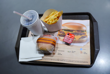 Tray with burger, fries, drink, and ketchup package with black markings.