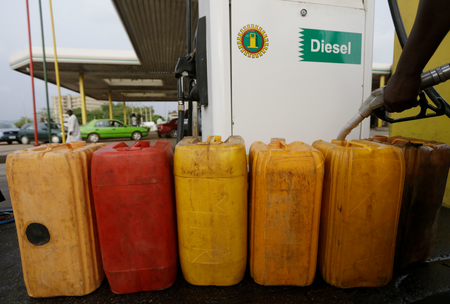 A man fills containers with diesel at a petrol station in Abuja