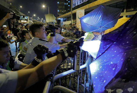 Protesters use umbrellas to block the pepper spray from police officers after clashing outside the Chinese central government&#039;s liaison office as thousands of people march in a Hong Kong down town street, Sunday, Nov. 6, 2016, to protest China&#039;s top legislative panel has said Beijing must intervene in a Hong Kong political dispute to deter advocates of independence for the city, calling such acts a threat to national security. (AP Photo/Vincent Yu)