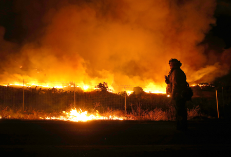 A firefighter monitors the Kincade Fire as it burns through the area on Oct. 24.