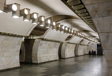an epty. subway station wit curved white marble walls and a row of lights