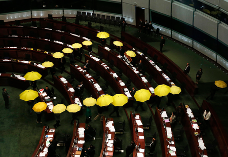 Pro-democracy lawmakers carrying yellow umbrellas, symbols for the Occupy Central movement, leave in the middle of a Legislative Council meeting as a gesture to boycott the government in Hong Kong