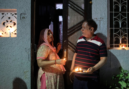 Residents stand with candles in their doorway in New Delhi.