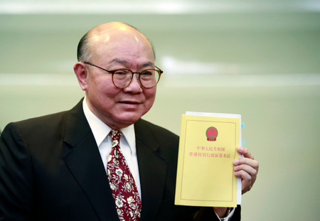 Retired judge Woo Kwok-hing holds a copy of the Basic Law, the territory&#039;s mini constitution, as he announces his run in next year&#039;s chief executive election during a news conference in Hong Kong, Thursday, Oct. 27, 2016. (AP Photo/Kin Cheung)