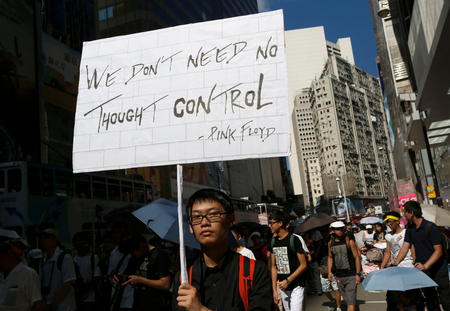 A protester holds a placard as thousands of people march in a down town street in Hong Kong Sunday, July 29, 2012.to protest the looming introduction of Chinese patriotism classes.