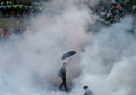 A protester walks in tear gas fired by riot policemen after thousands of protesters blocking the main street to the financial Central district outside the government headquarters in Hong Kong September 28, 2014.