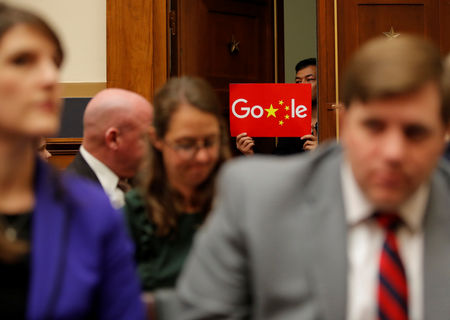 A demonstrator holds up a sign in the doorway as Google CEO Sundar Pichai testifies at a House Judiciary Committee on greater transparency in Washington, U.S., December 11, 2018. REUTERS/Jim Young - RC19CFD97160