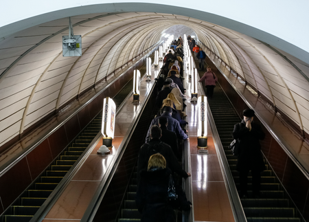 people riding an underground elevator through a white tunnel in Kyiv, Ukraine