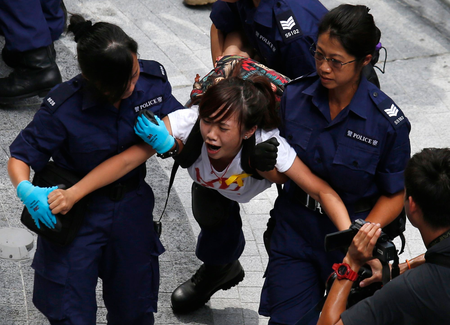 A protester reacts as she is dragged away by police after storming in government headquarters in Hong Kon