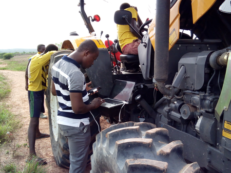 A tractor operator helps a farmer with a request made through the Trotro Tractor service, where farmers dial a code to book a tractor to plow their land.