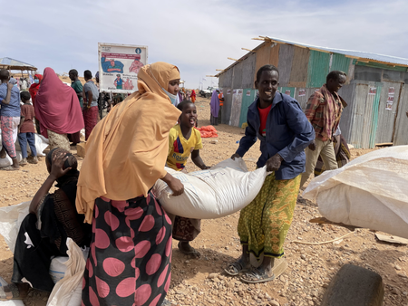 Uma família na Etiópia carrega um saco de grãos de emergência em um carrinho.