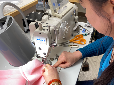 An employee of Kaas Tailored sews a mask