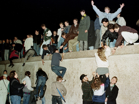 East German citizens climb the Berlin wall at the Brandenburg Gate as they celebrate the opening of the East German border in this November 10, 1989 file photo.
