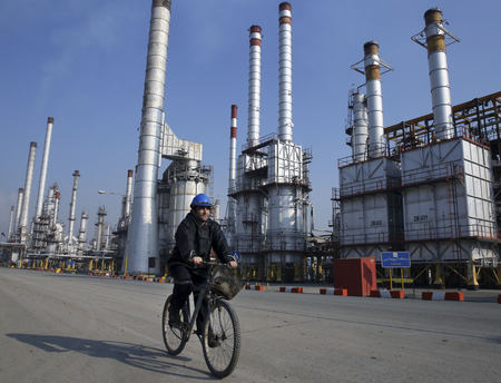 An Iranian oil worker rides his bicycle at the Tehran oil refinery, south of the capital Tehran, Iran. Across a Mideast fueled by oil production, low global prices have some countries running on empty and scrambling to cover shortfalls, even as more regional crude is on tap to enter the market.