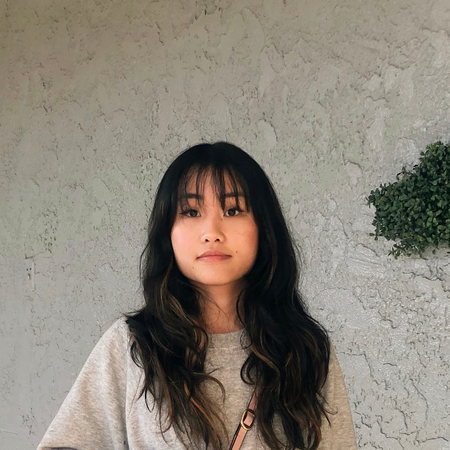 A portrait of Frances Hyunh wearing a serious face in a white sweater.