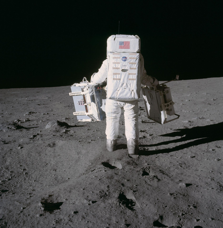 Buzz Aldrin carries scientific experiments on the surface of the moon.