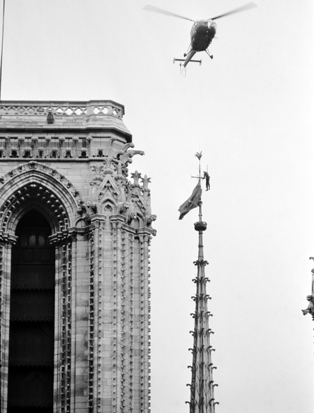 A Paris fire department helicopter hovers over Notre Dame Cathedral, in Paris, on Jan. 19, 1969, and lowers a fireman, dangling on the end of a line, to remove a blue and red South Vietnamese National Liberation Front, Viet Cong, flag placed on a 250-foot Cathedral spire.