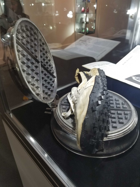 A pair of Nike shoes from 1972 with the waffle tread sole, sitting atop a waffle iron