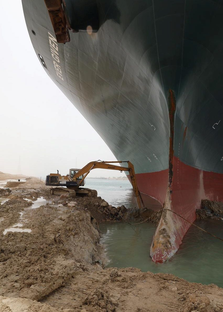 An excavator attempts to free stranded container ship Ever Given, one of the world&#039;s largest container ships, after it ran aground, in the Suez Canal.