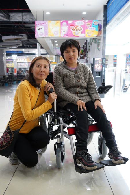 Aigul Orozbayeva and her daughter in the newly-bought electronic wheelchair came to Khorgos ICBC from Bishkek, Kyrgyzstan.