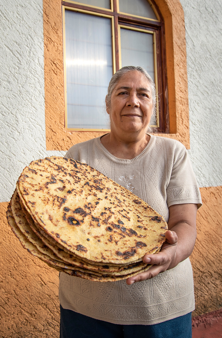 Woman posing with tortillas made from local maize