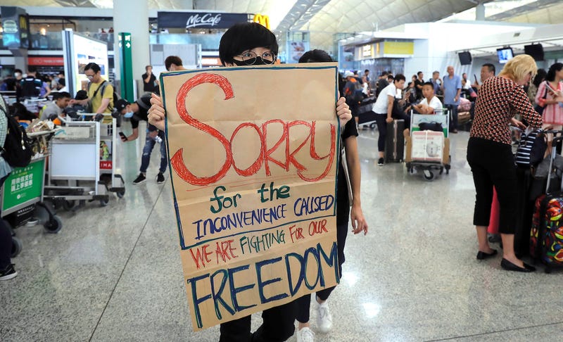 A protester shows a placard to stranded travelers during a demonstration at the Airport in Hong Kong earlier this week