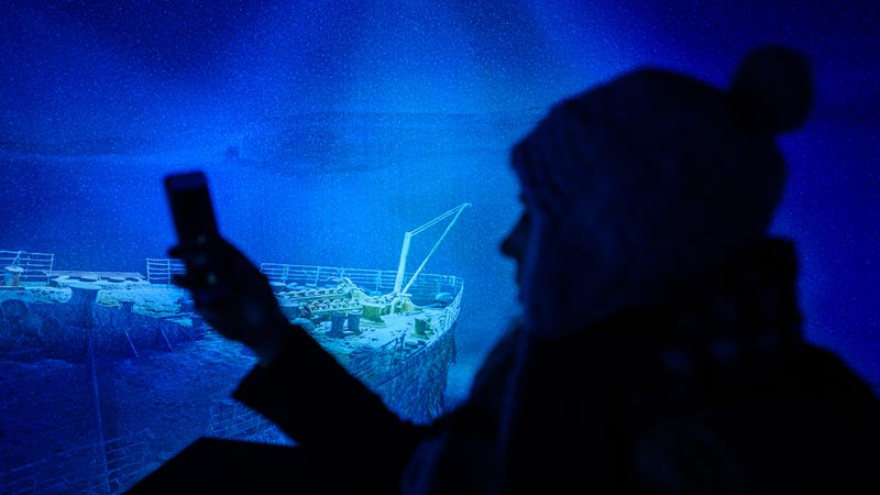 A woman takes a picture at a replica of the shipwreck