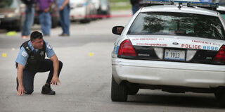 Chicago police officer inspects a crime scene after a spate of violence over the July Fourth holiday. (Scott Olson/Getty Images)