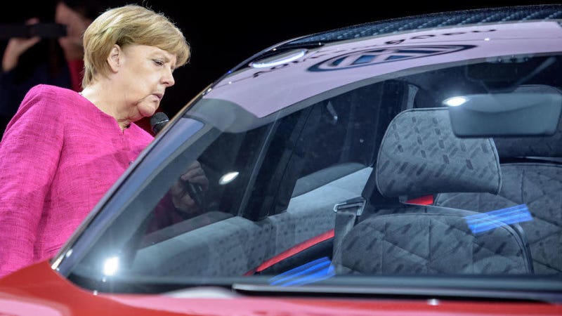 FRANKFURT AM MAIN, GERMANY - SEPTEMBER 14: The German Chancellor Angela Merkel looks into a Volkswagen ID Crozz electric crossover concept car during her visit at the 2017 Frankfurt Auto Show âInternationale Automobil Ausstellungâ (IAA) on September 14, 2017 in Frankfurt am Main, Germany. The Frankfurt Auto Show is taking place during a turbulent period for the auto industry. Leading companies have been rocked by the self-inflicted diesel emissions scandal. At the same time the industry is on the verge of a new era as automakers commit themselves more and more to a future that will one day be dominated by electric cars