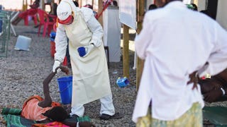 A health worker wearing protective equipment assists an Ebola patient at the Kenema, Sierra Leone, treatment center run by the Red Cross Society Nov. 15, 2014. FRANCISCO LEONG/AFP/Getty Images