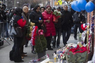 Emerald Garner (center left, holding blue candle), daughter of Eric Garner, visits a makeshift memorial near the site where two New York City police officers were slain. Yahoo Screenshot
