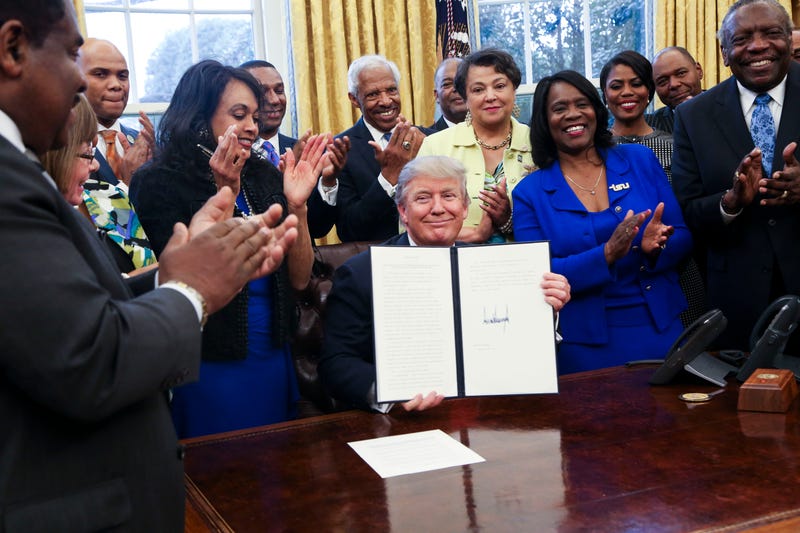 President Donald Trump shows the signed executive order supporting black colleges and universities in the Oval Office of the White House February 28, 2017 in Washington, DC.