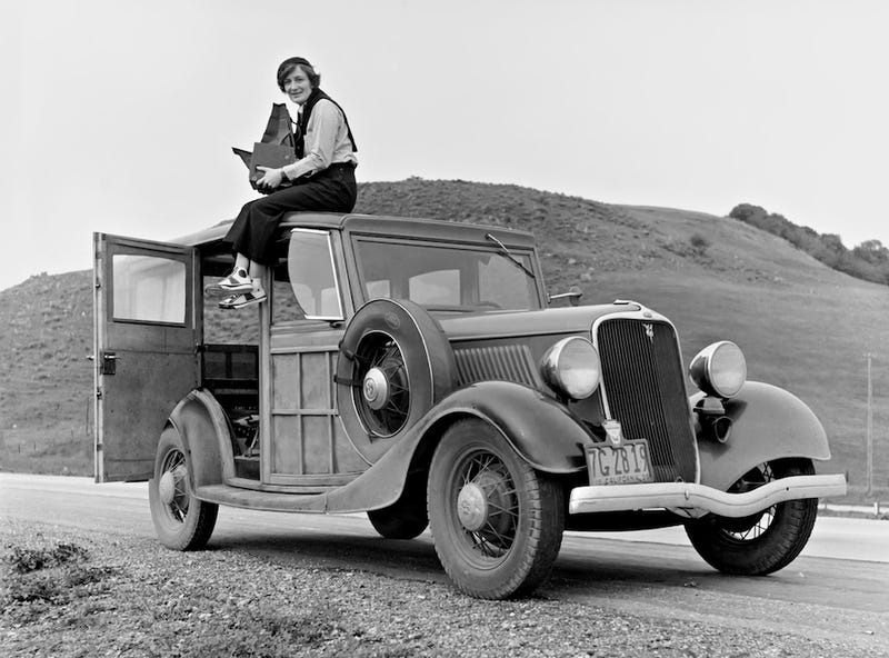 Lange sits atop a Ford Model 40 in California in 1936. She is holding a Graflex 4×5 Series D camera. (US Library of Congress)