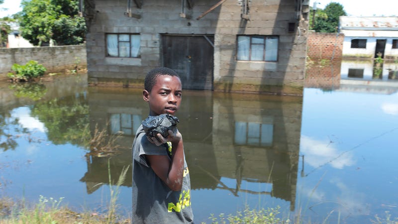 A young boy walks past a flooded home in Inchope, Mozambique, March 25, 2019.