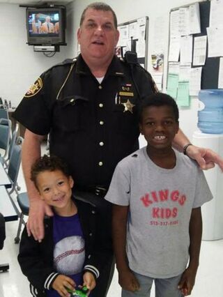 Butler County Sheriff’s Deputy Brian Bussell poses with the two small children of the woman he helped out. Butler County Sheriff’s Office via the Cincinnati Enquirer 