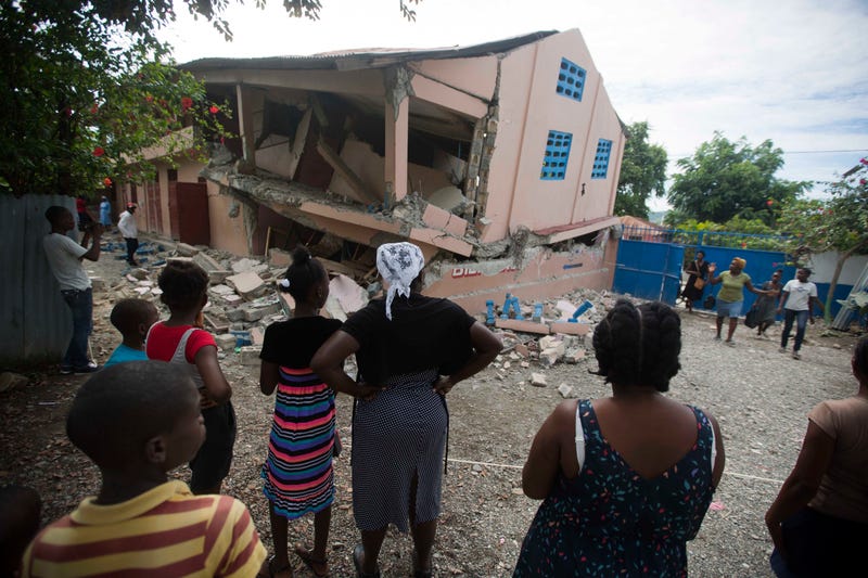 Residents stand looking at a collapsed school damaged bya magnitude 5.9 earthquake the night before, in Gros Morne, Haiti, Sunday, Oct. 7, 2018. Emergency teams worked to provide relief in Haiti on Sunday after the quake killed at least 11 people and left dozens injured.