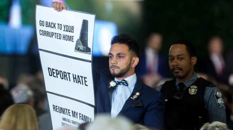Virginia state Del. Ibraheem Samirah holds up a sign as Donald Trump delivers remarks during the 400th anniversary celebration of the first representative legislative assembly at Jamestown on July 30, 2019, in Jamestown, Va.