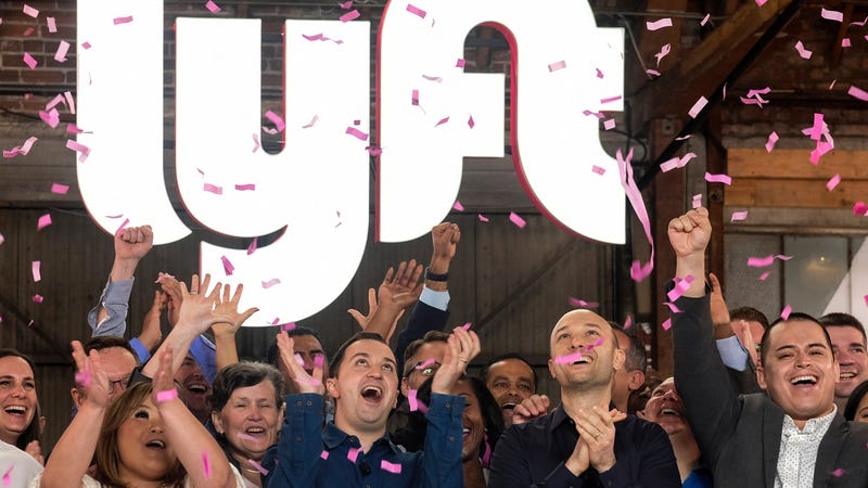 Lyft co-founders John Zimmer, front second from left, and Logan Green, front second from right, cheer as they as they ring a ceremonial opening bell in Los Angeles.