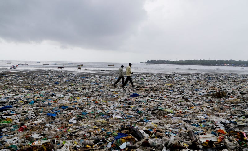 In this Aug. 19, 2017 photo, people walk past plastic bags and garbage on the Arabian Sea coast in Mumbai, India. Photo: AP