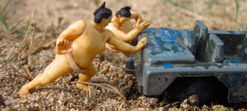Illustration for article titled Tiny Sumo Wrestlers Pushing A Derelict Jeep Need A Haiku Caption