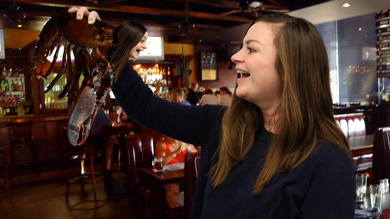 A lobster with a human head identical to the woman holding it.