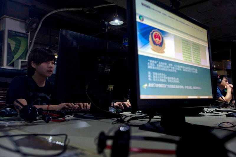 Computer users sit near a monitor display with a message from the Chinese police on the proper use of the Internet (Associated Press)