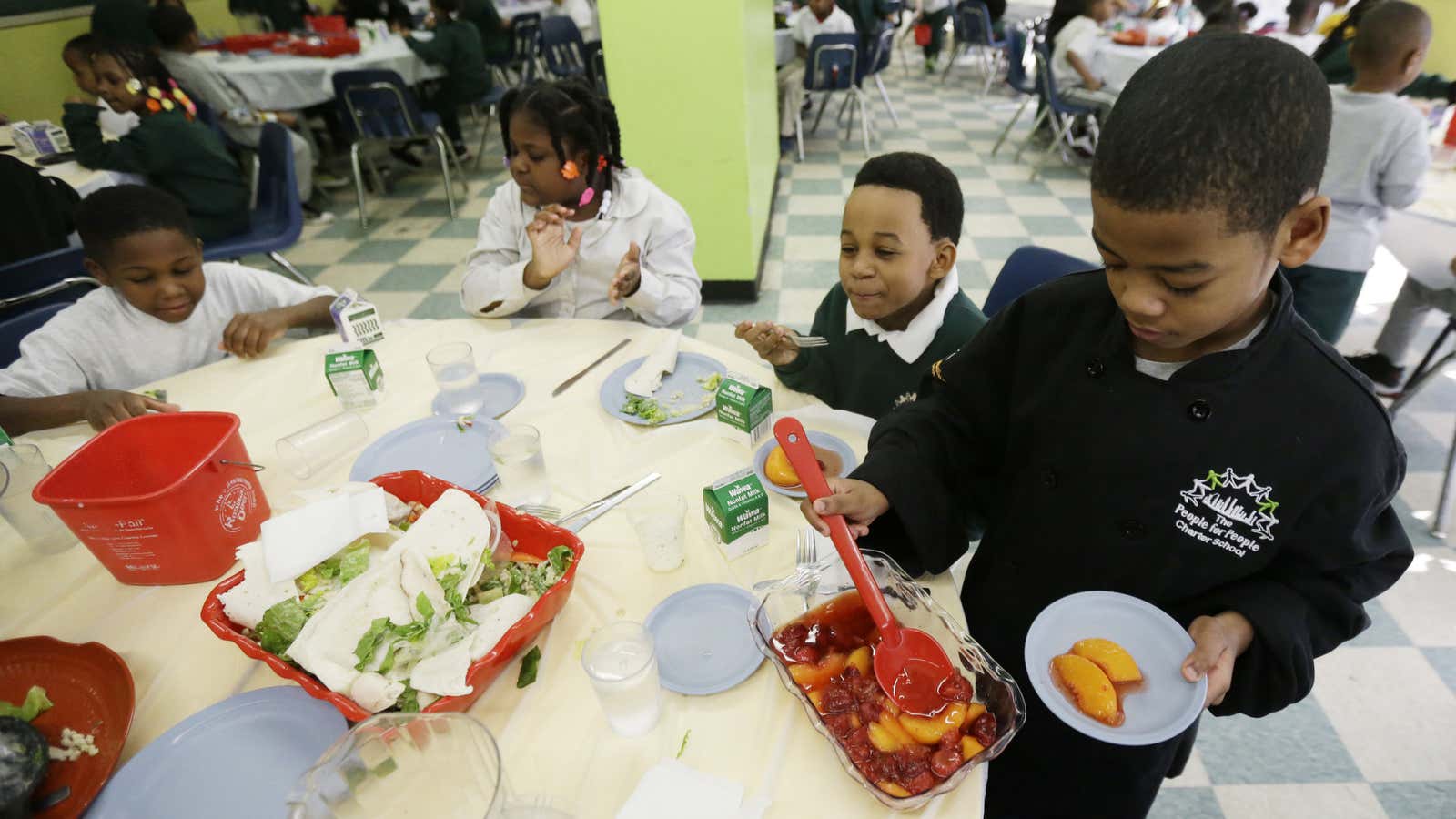 A student serves dessert to his fellow classmates at a charter school in Philadelphia, Pennsylvania where manners are reinforced.