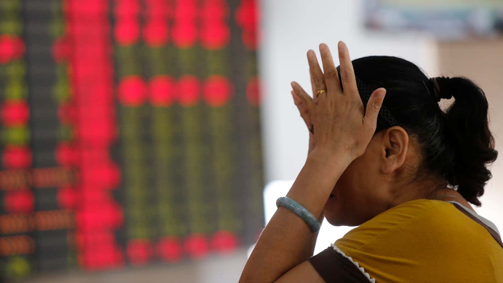 An investor gestures as she looks at the stock price monitor at a private securities company Friday Aug. 10, 2012. Asian stock markets tumbled Friday…