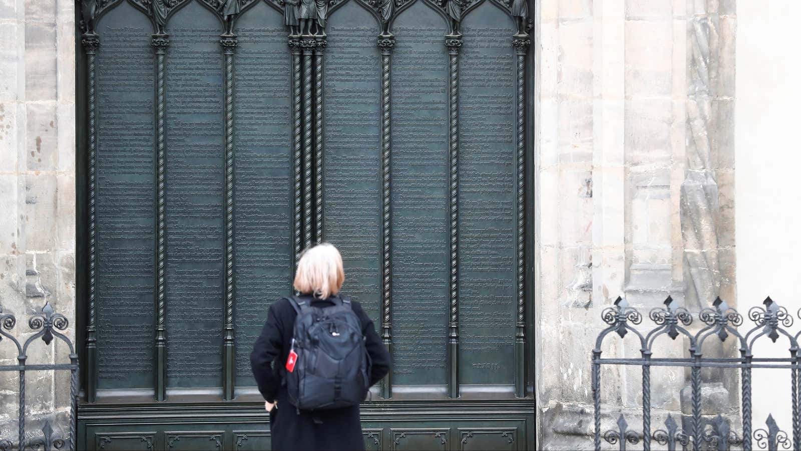A woman looks at German theologian Martin Luther’s theses door during the 500th Anniversary of the Reformation.