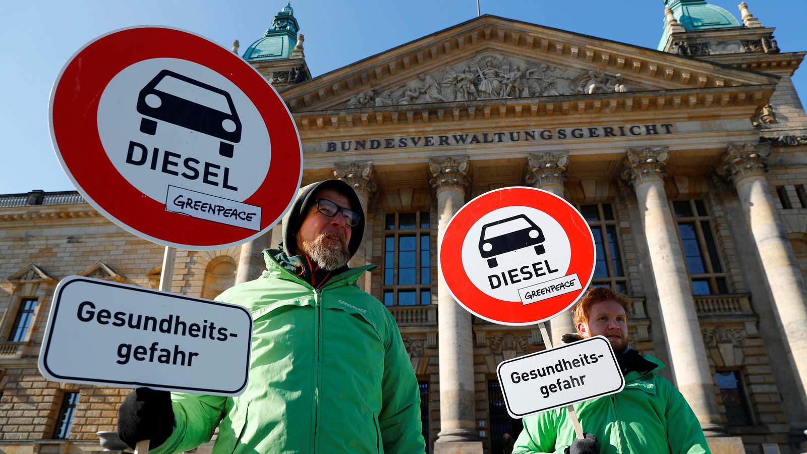 Greenpeace activists hold “health risk” signs outside the court in Leipzig.