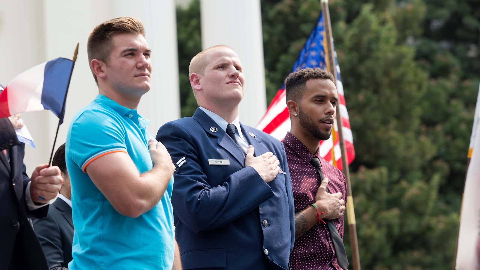 Spencer Stone, center, stands with two friends during a parade held in their honor, after the three stopped an armed gunman from attacking a French train.