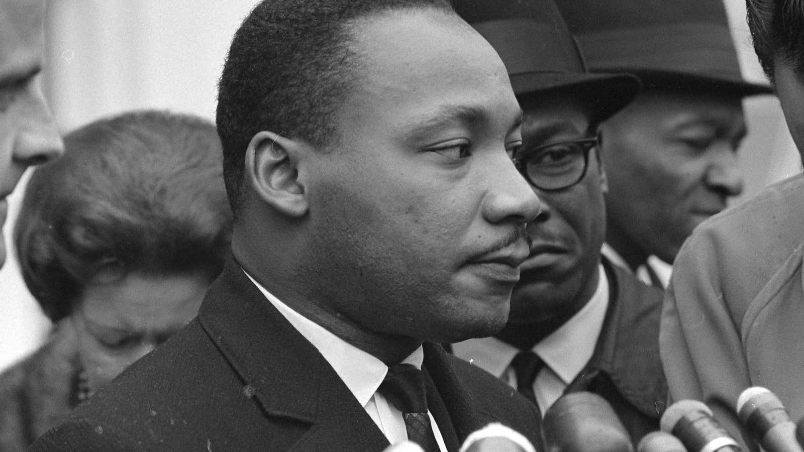 Martin Luther King Jr. stands before microphones ready to speak after meeting with President Lyndon B. Johnson to discuss civil rights at the White House…
